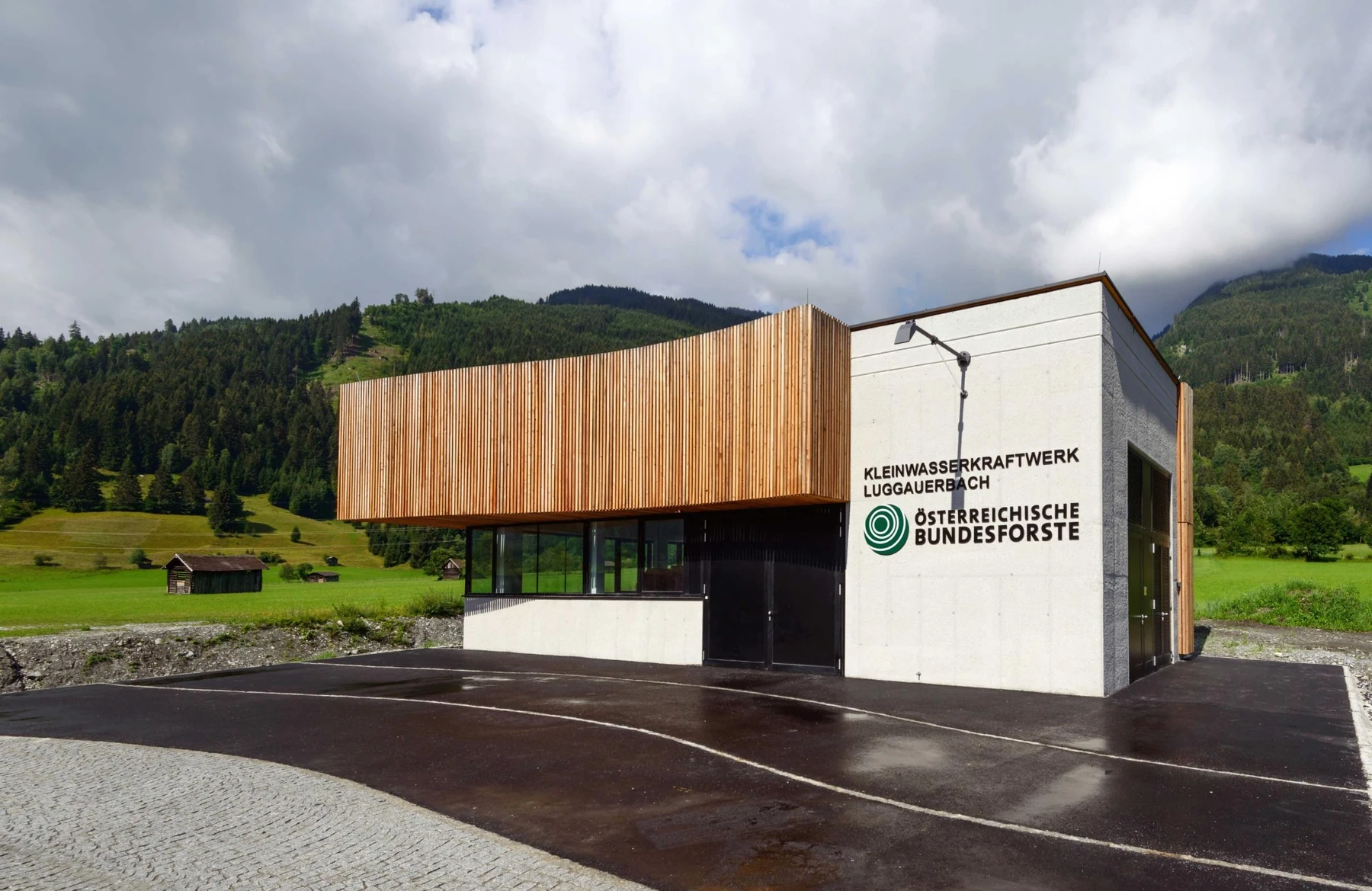 Kleinkraftwerksgebäude mit Holz- und Betonfassade in alpiner Umgebung